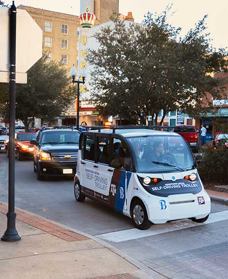 Texas A&M branded autonomous shuttle driving in downtown Bryan